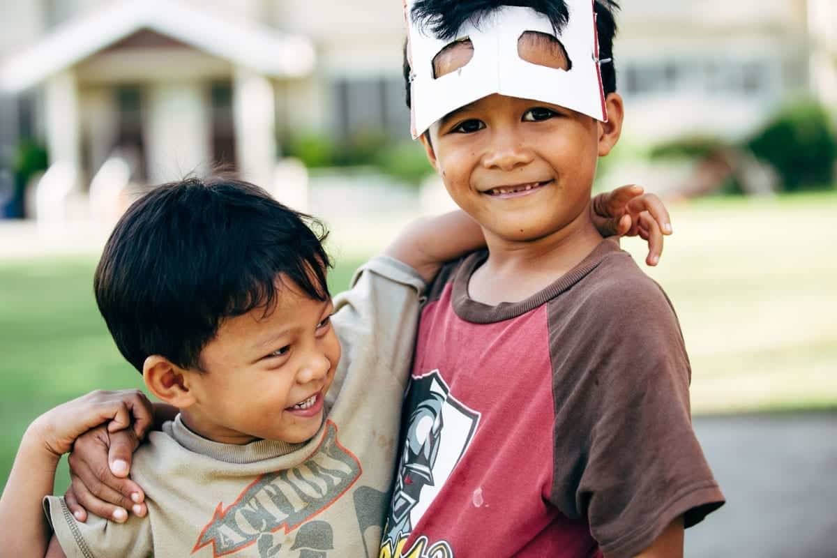Young boys hugging and looking at camera.