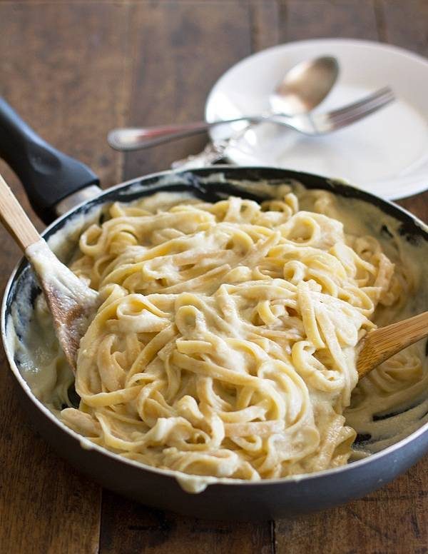 Alfredo with cauliflower sauce in a skillet with wooden spoons.