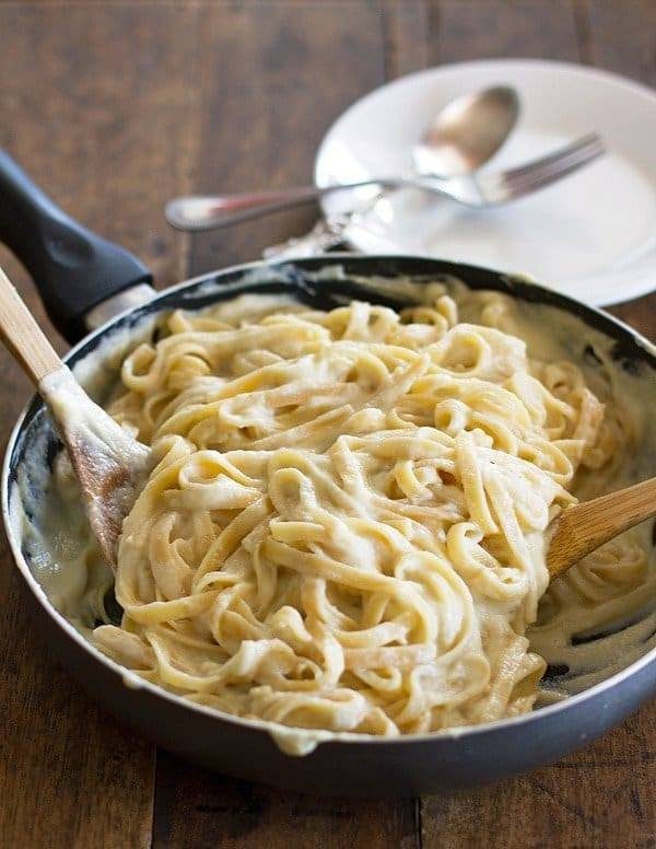 Healthy Fettuccine Cauliflower Alfredo in a pan with wooden spoons.