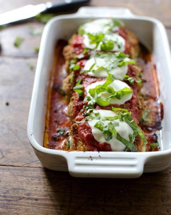 Baked mozzarella chicken rolls in a white baking dish.