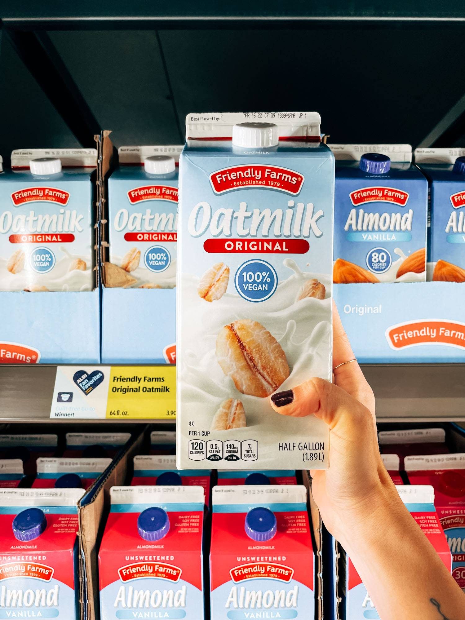 White hand holding a carton of oatmilk