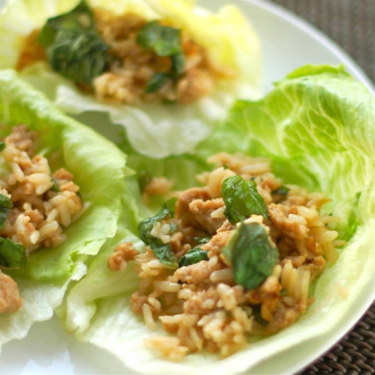 Basil chicken lettuce wraps on a white plate.