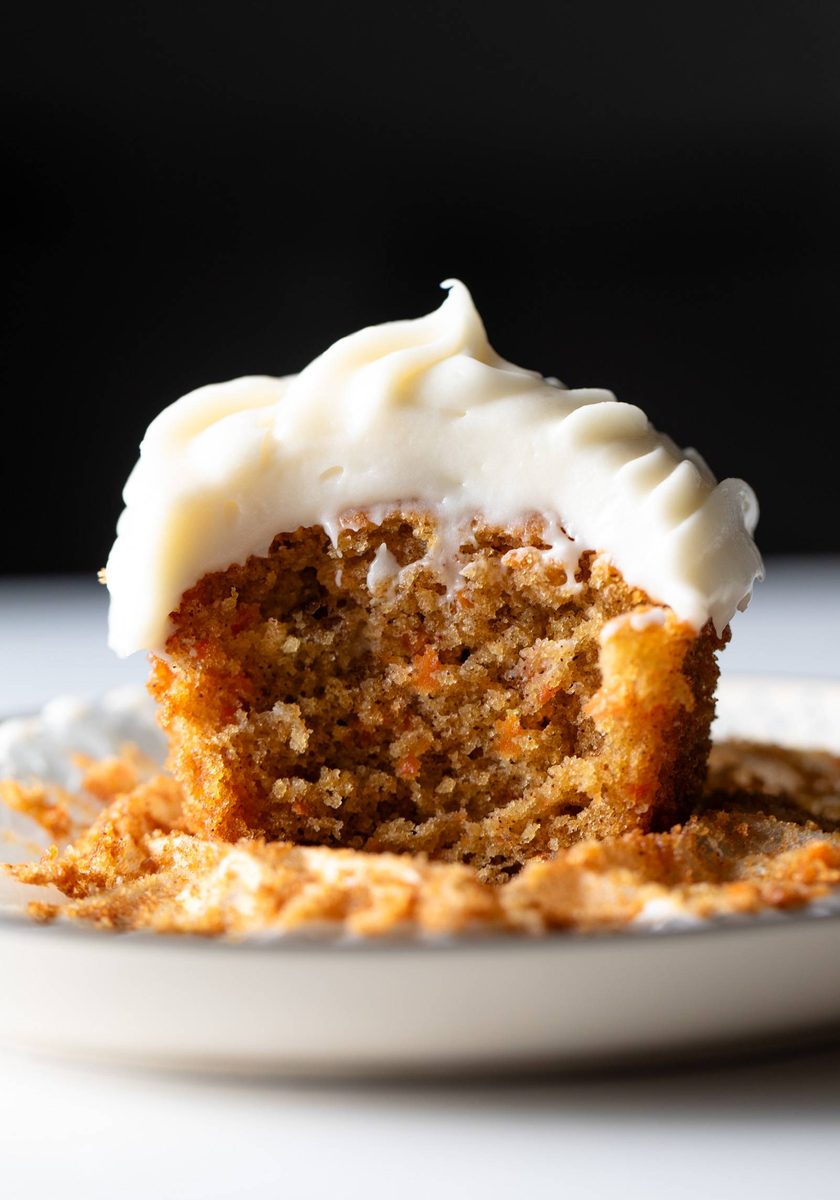 Carrot cake cupcake with cream cheese frosting on a plate.