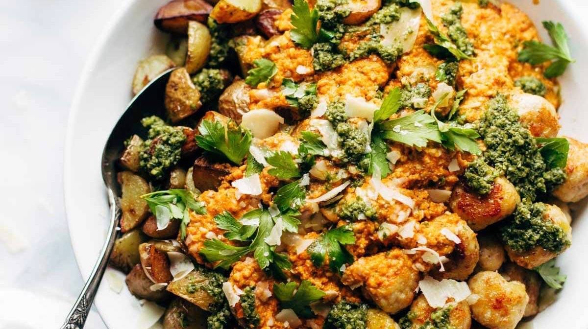 Mini Chicken Meatballs with roasted potatoes and romesco sauce in a bowl.