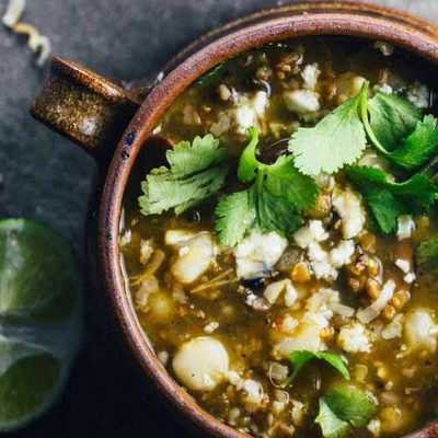 Mushroom Poblano Posole Verde in bowls with a spoon.