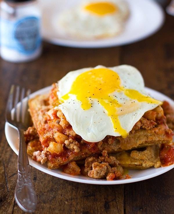 Chili and cornbread waffle stacks with an egg on a plate with a fork.