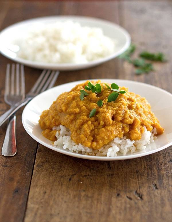 Red lentil dhal on a white plate with two forks.