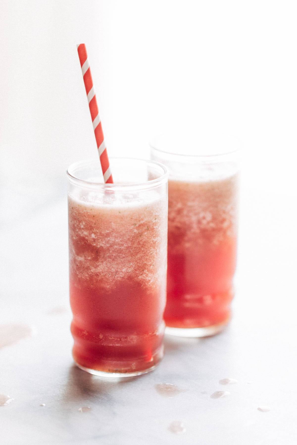 Two pink smoothies with a straw.